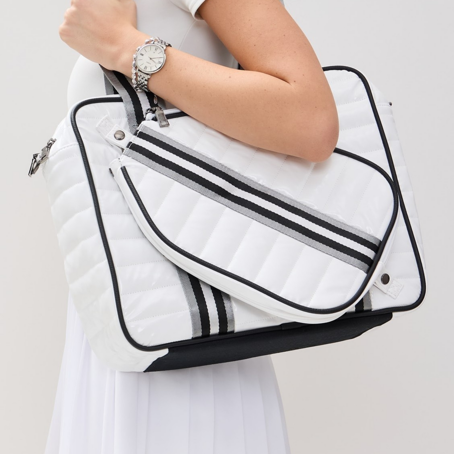 Best pickleball bag for women – white puffer tote with paddle cover worn over shoulder.